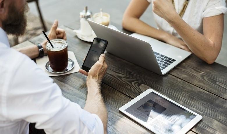 deux personnes à l'ordinateur et sur téléphone portable