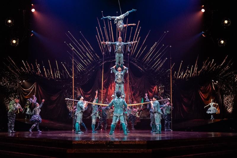 une scène spectaculaire d'un spectacle du Cirque du Soleil, mettant en vedette des acrobates effectuant une pyramide humaine complexe sur un fond théâtral