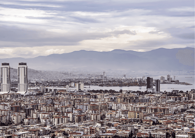 Vue panoramique d'Izmir en mars 2025, avec ses gratte-ciel modernes, son littoral et les montagnes en arrière-plan.