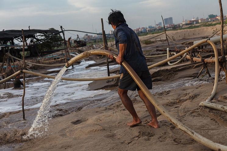 Un homme mélange de l'eau avec le sable pour l'extraire