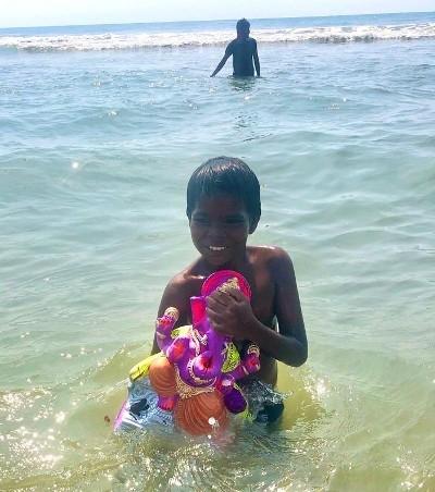 Un enfant et sa statue de Ganesh dans la mer à Pondichéry