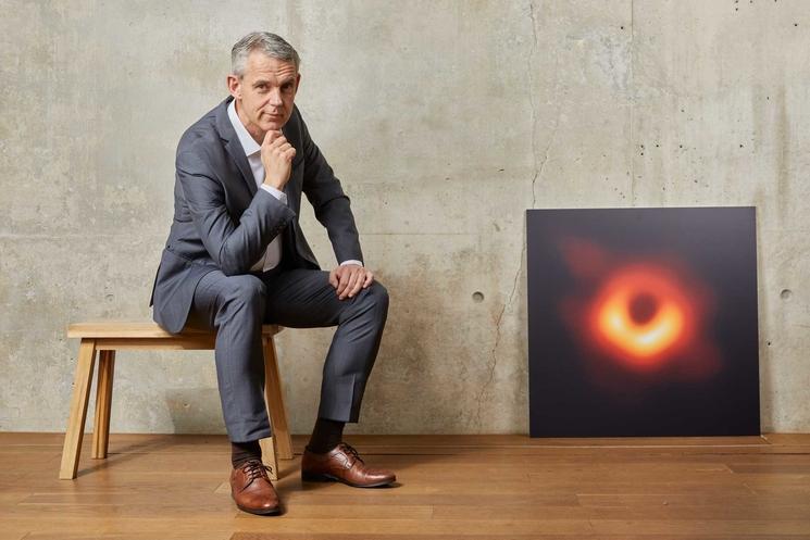 Photo d'Heino Falcke qui pose à côté de sa photo de trou noir