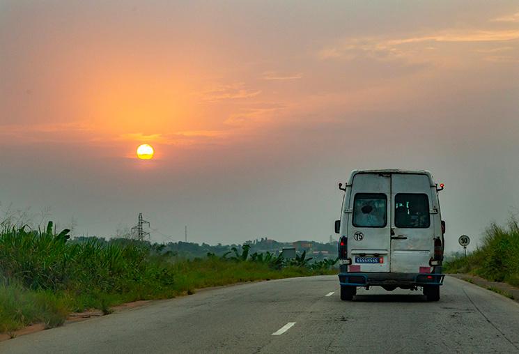 Une camionnette sur une route devant un coucher de Soleil près d'Abidjan