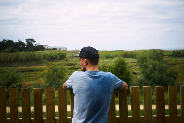 Jeune homme regarde dans le vide par dessus une rambarde