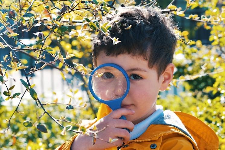 Un enfant de maternelle avec une loupe à la main