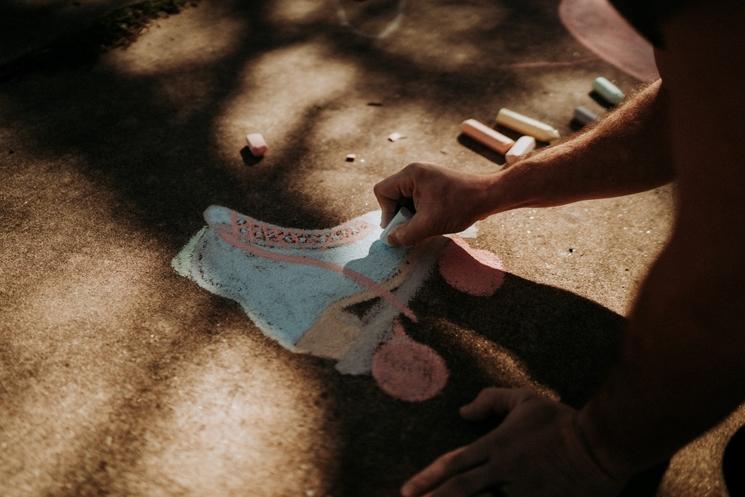 Un adolescent expatrié réalise un dessin sur le sol 