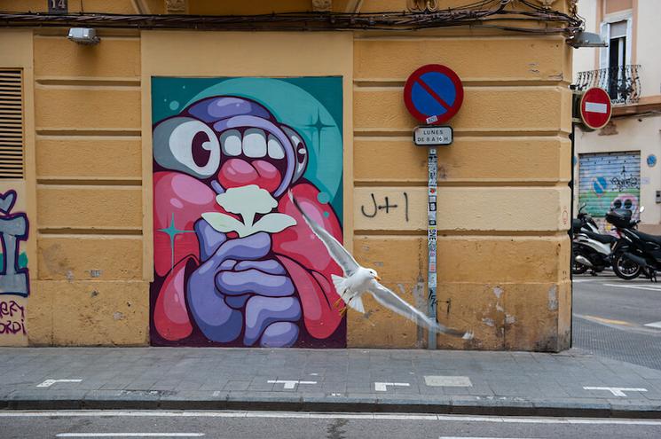 un mur jaune avec un tag rouge et violet et une mouette en train de voler