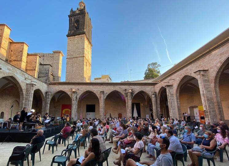 un public assis lors d'un concert de musique dans un cloître 