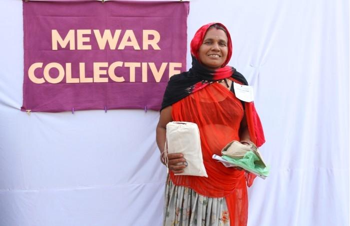 Une femme de Rajasthan devant le logo de Mewar Collective