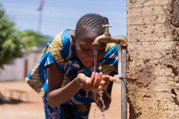 jeune fille africaine buvant de l'eau du robinet