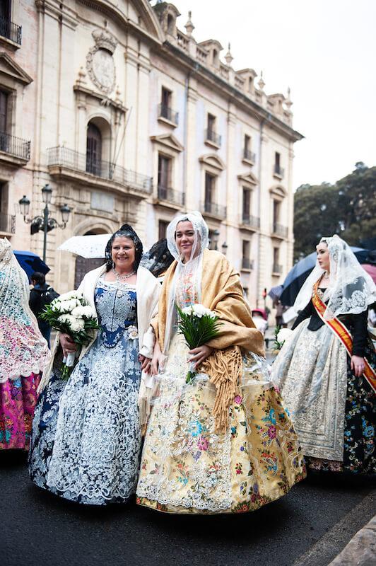 des femmes habillées en robes traditionnelles avec des bouquets dans leurs mains