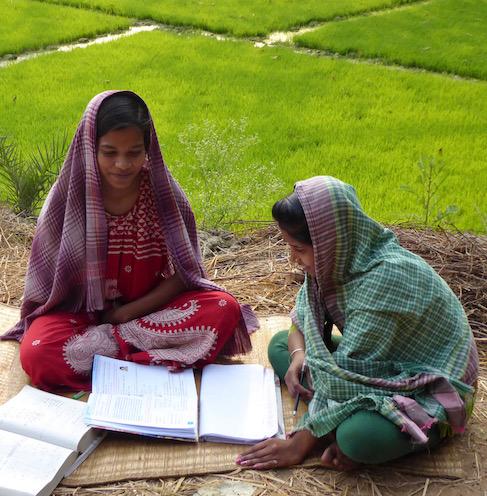 Des jeunes filles faisant leurs devoirs dans un champ au Bengale