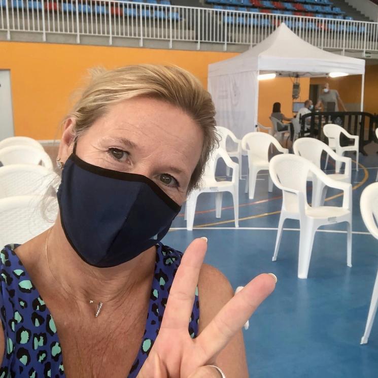 Une femme blonde avec un masque noir dans un centre de vaccination