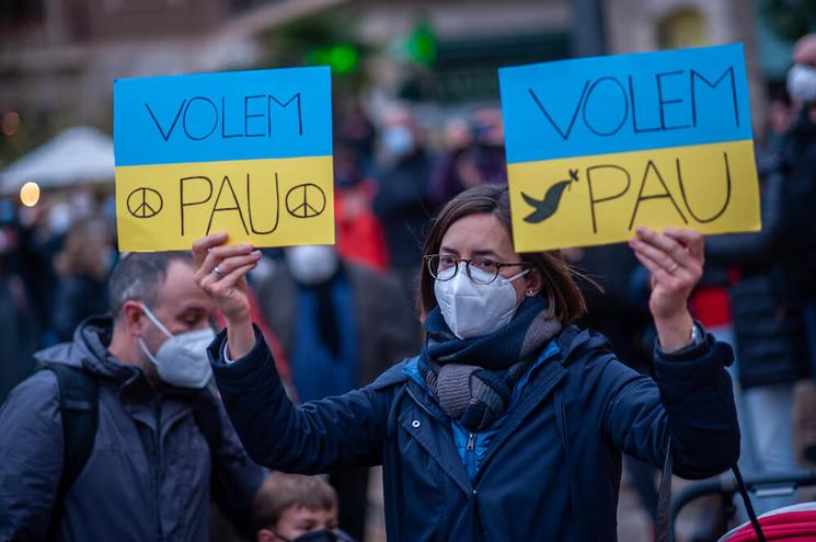 Une femme en train de manifester avec deux pancartes bleues et jaunes