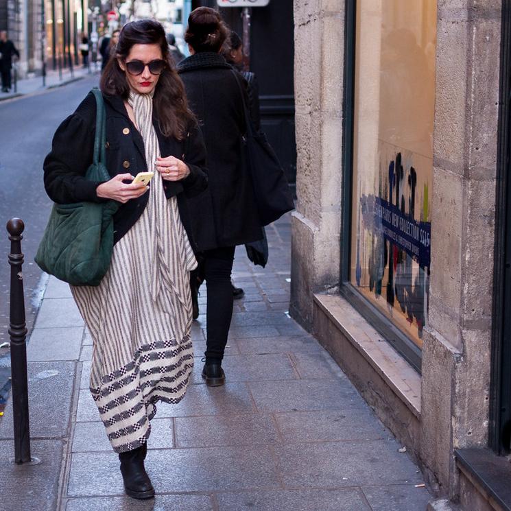 une femme en train de marcher avec un portable dans la main et des lunettes de soleil