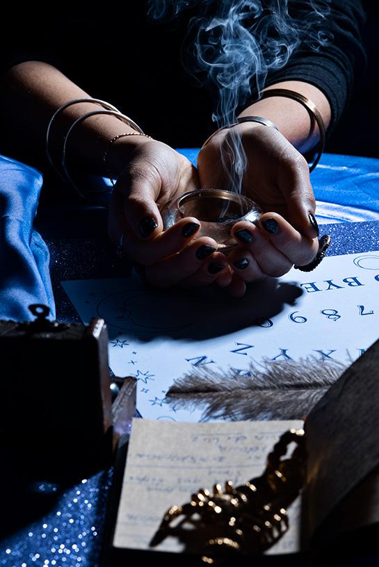 Mains de femmes posées sur une table, pratiquant un rituel avec de l'encens