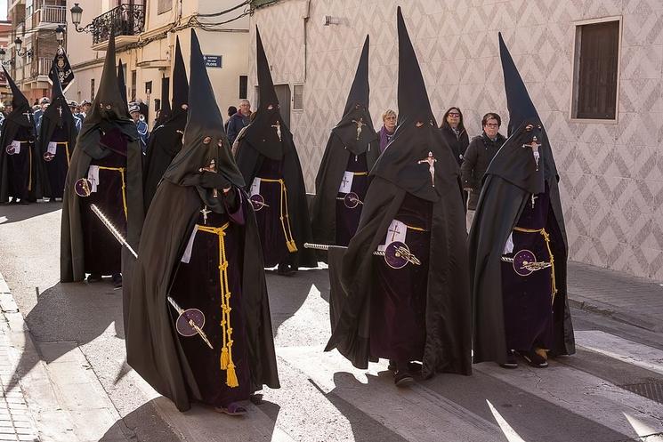 des personnes en train de marcher habillées en noir avec des capuches 