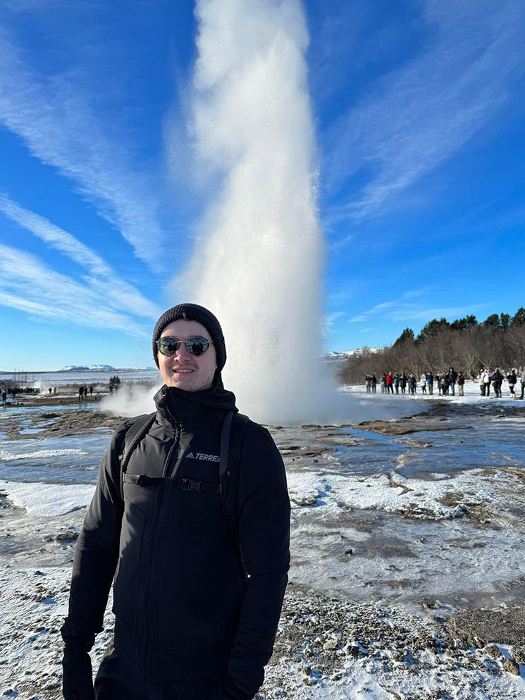 Tim souriant devant un geizer en Islande