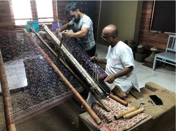 Deux artisans fabriquent un patola sur le métier à tisser