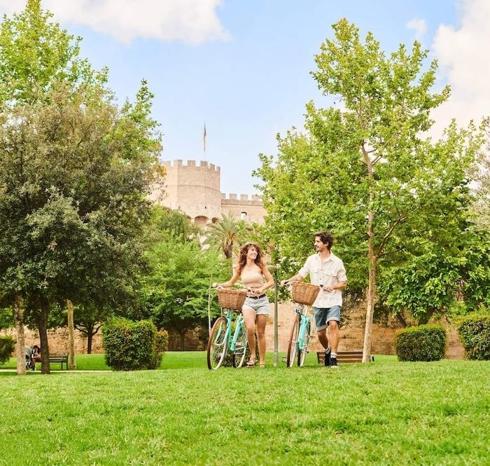 des touristes à pied avec leur vélo dans le jardin du turia à valence