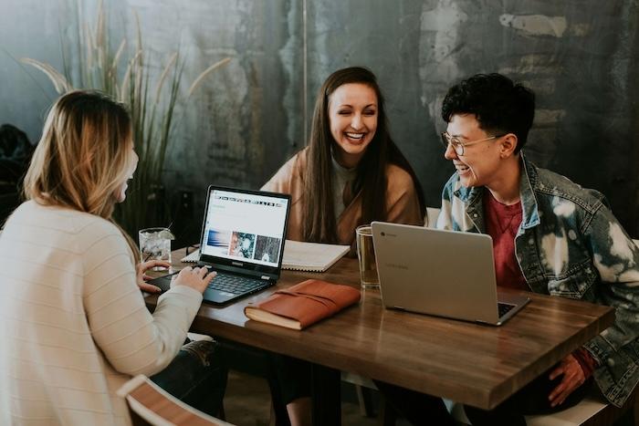 trois femmes assises devant une table et riant ensemble