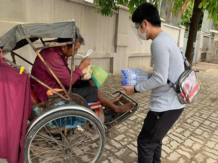 un jeune cambodgien offre de la nourriture à un cyclopousse