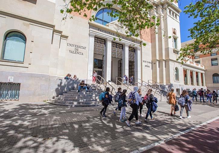 des personnes en train de marcher devant l'entrée de l'universidad de valencia