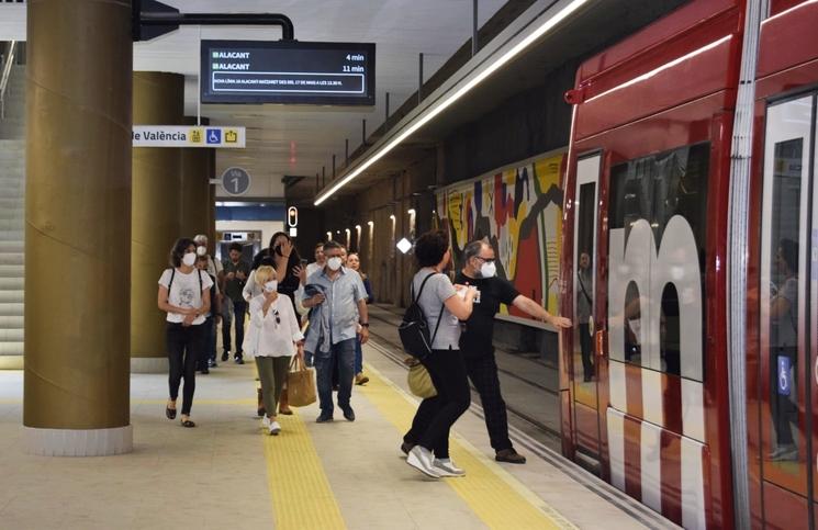 des personnes en train de marcher avec des masques sur le quai dans une station de metro