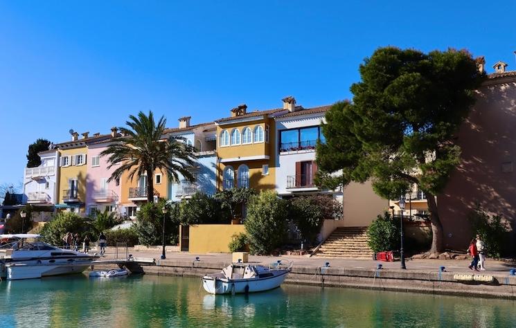 des bateaux sur un petit port avec un palmier et des maisons aux façades colorées