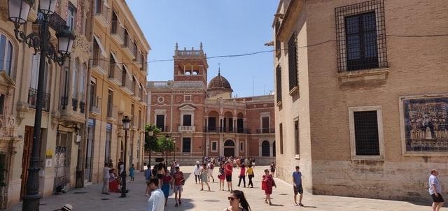 une place dans une ville avec un ciel bleu et des passants