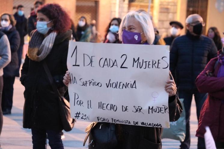 une femme avec un masque et une affiche contre les féminicides